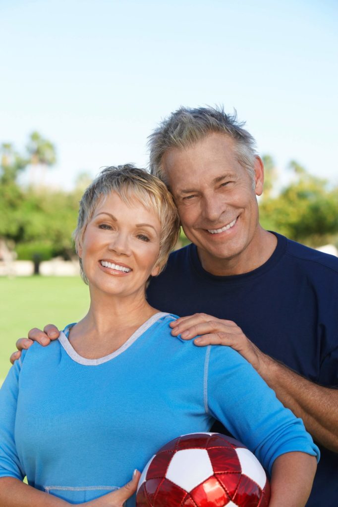 senior couple outside smiling with soccer ball