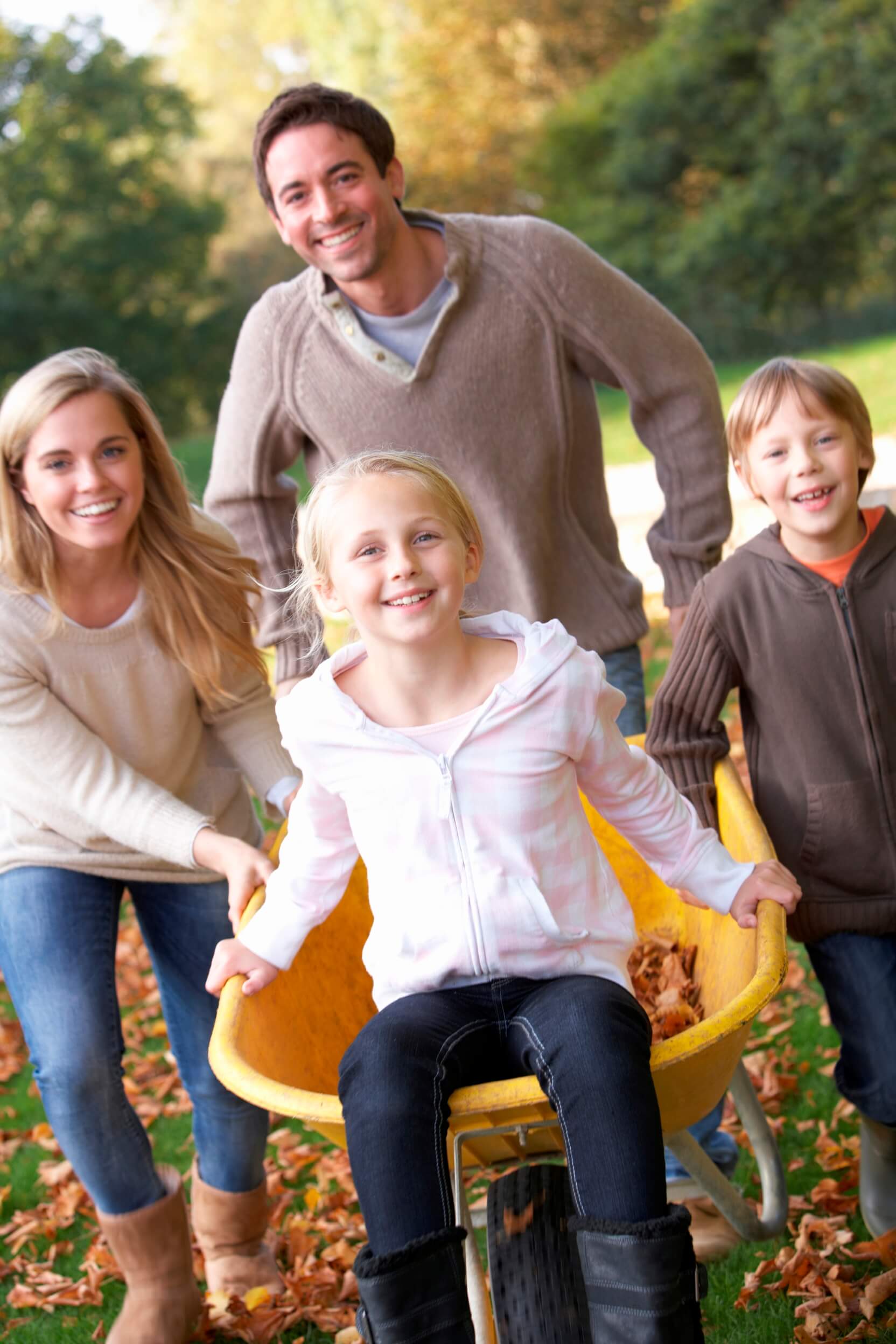 family outside smiling with wheel barrel